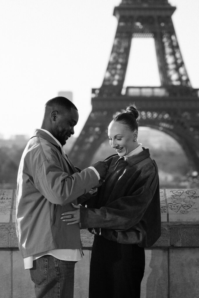couple putting on engagement ring black and white